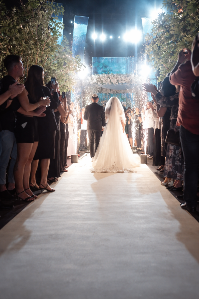 כניסת חתן וכלה לחתונה באולם אירועים יסמין בקריות עם שביל מואר ואורחים משני הצדדים